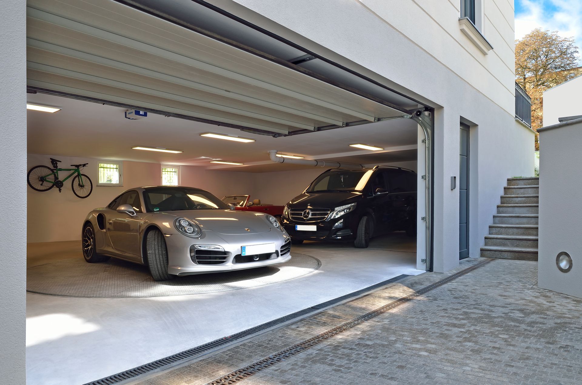 To biler er parkeret i en garage med åben dør
