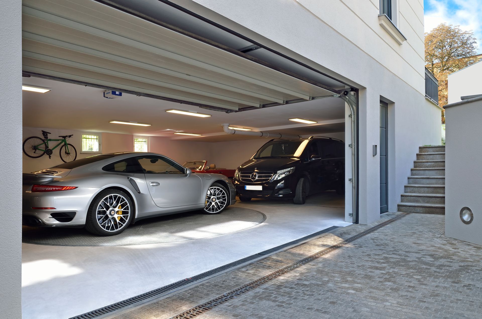 To biler er parkeret i en garage med åben dør
