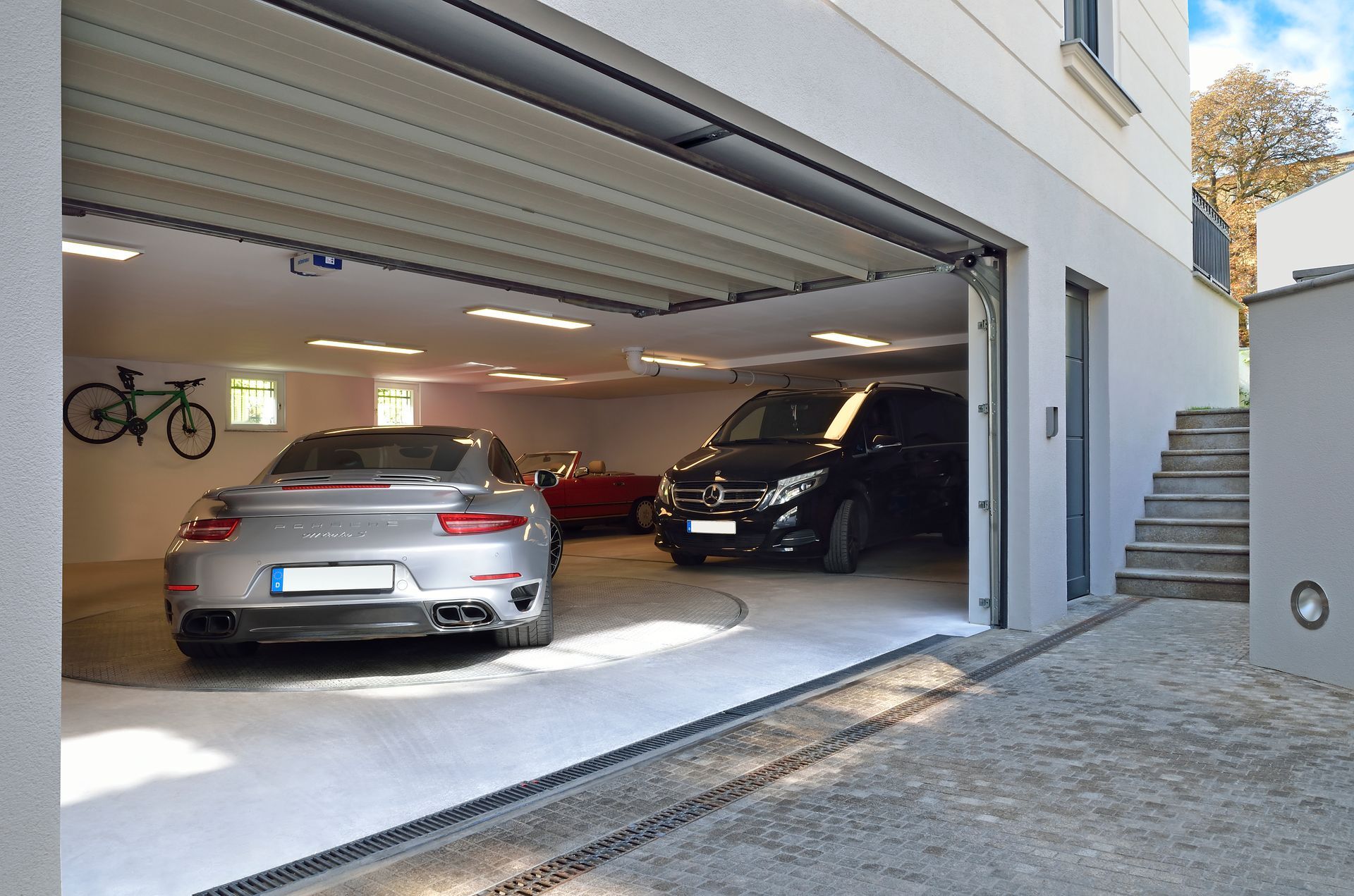 To biler er parkeret i en garage med åben dør