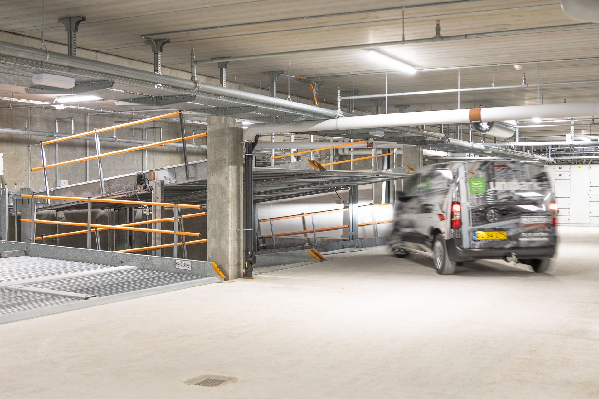 A car is driving down a ramp in a parking garage.