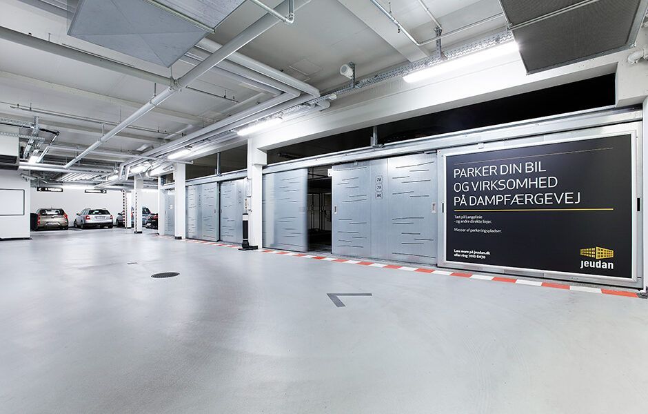 En meget stor underjordisk parkeringskælder med biler parkeret i den.
