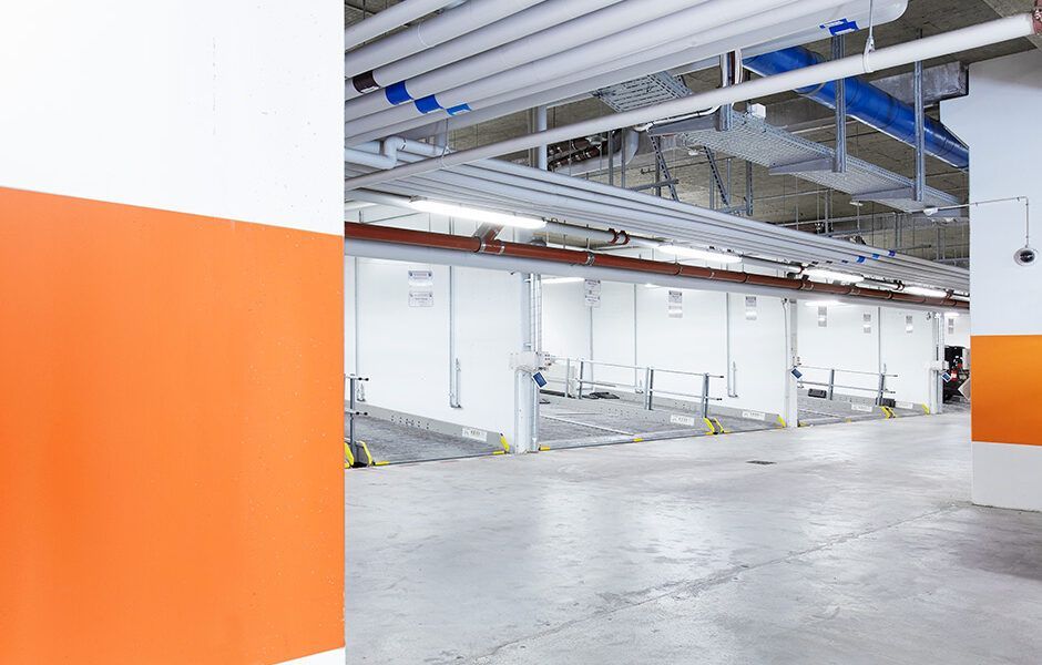 Et tomt parkeringshus med orange og hvide vægge og et betongulv.