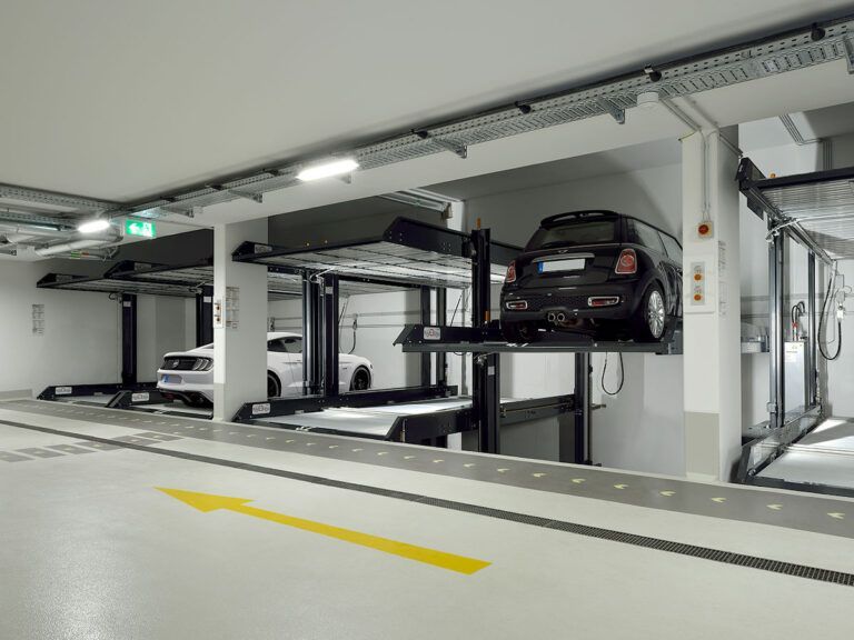 To biler er parkeret på en elevator i en parkeringskælder