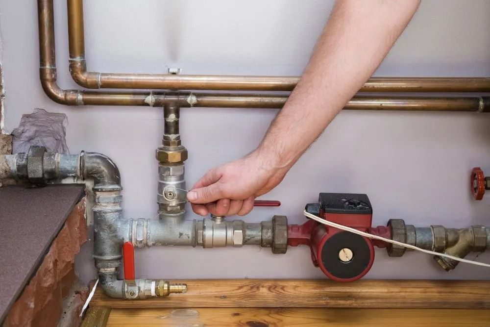 Person's Hand Turning a Valve on Plumbing Pipes — MCA Plumbing & Drainage in Jensen, QLD