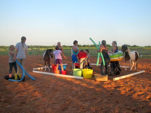 A group of people are playing in the dirt with horses - Anna, TX - Spirit Song Youth Equestrian Academy