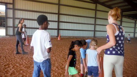 A group of children are standing in the dirt in a barn - Anna, TX - Spirit Song Youth Equestrian Academy