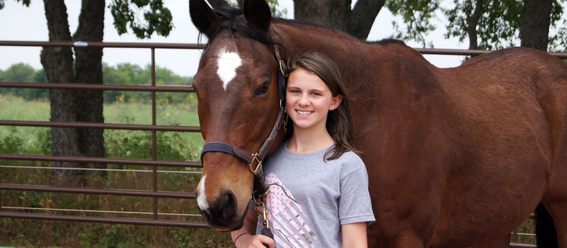 A young girl is standing next to a brown horse - Anna, TX - Spirit Song Youth Equestrian Academy