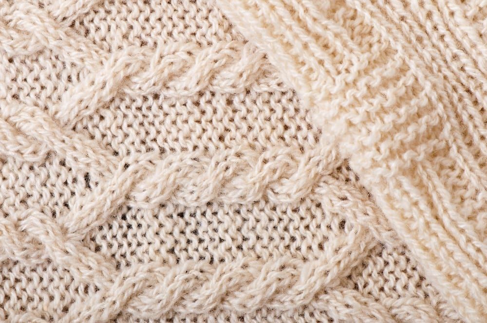 A close up of a white knitted fabric with a pattern.