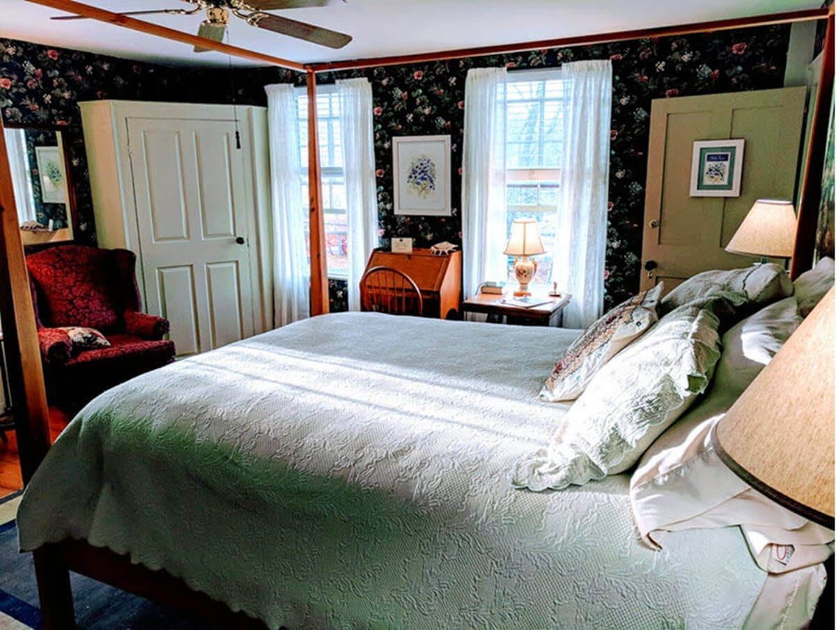 A bedroom with a four poster bed and a chair