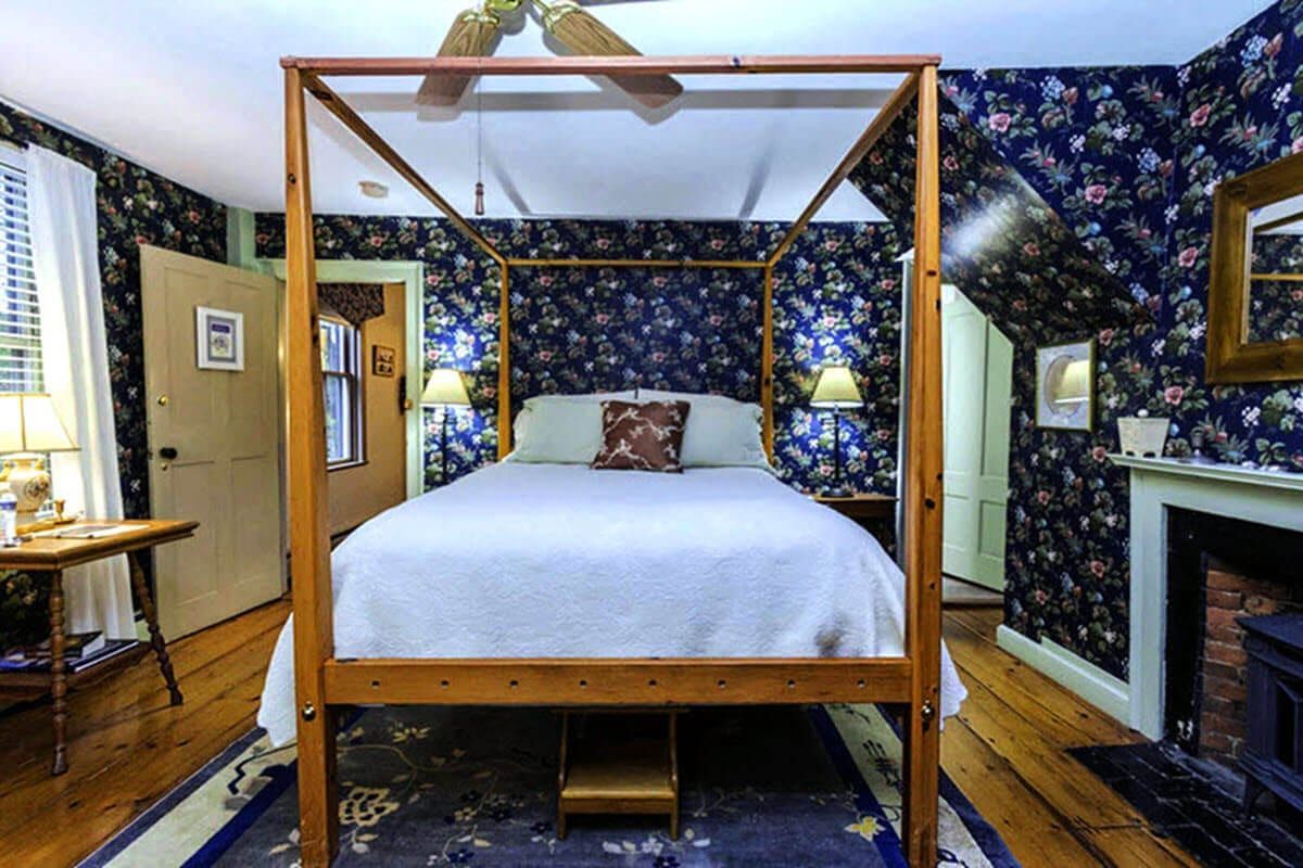 A bedroom with a four poster bed and a fireplace