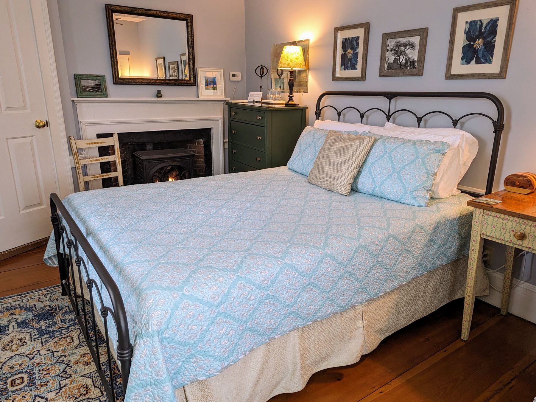 A bedroom with a bed , nightstand , mirror and fireplace.