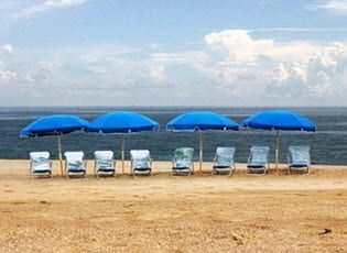 A row of blue umbrellas and chairs on a beach