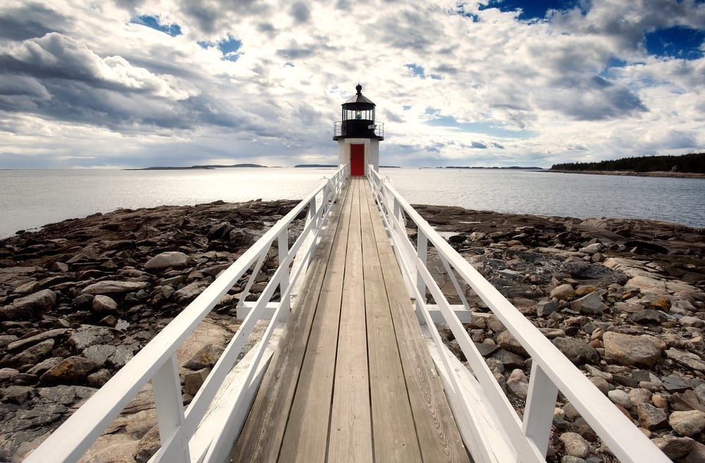A wooden pier leading to a lighthouse in the ocean