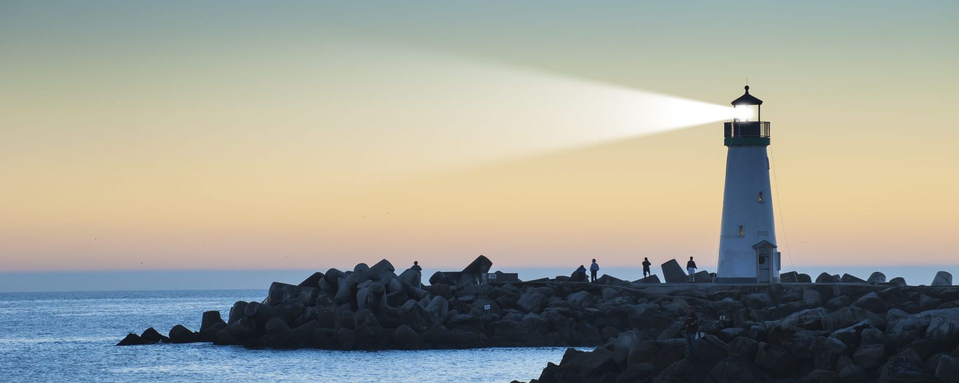 A lighthouse on a rocky island in the middle of the ocean.