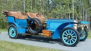 An old blue car is parked on the side of the road.