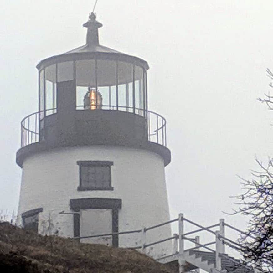 A lighthouse on top of a hill with stairs leading up to it.