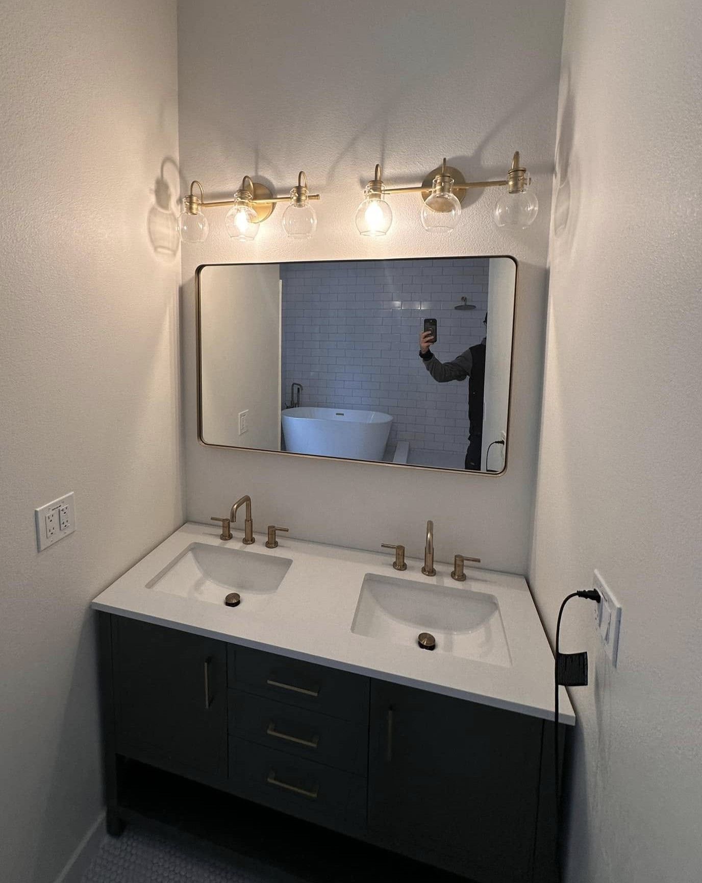 Bathroom with a dark blue vanity, white countertop, gold fixtures, and a mirror reflecting the room.