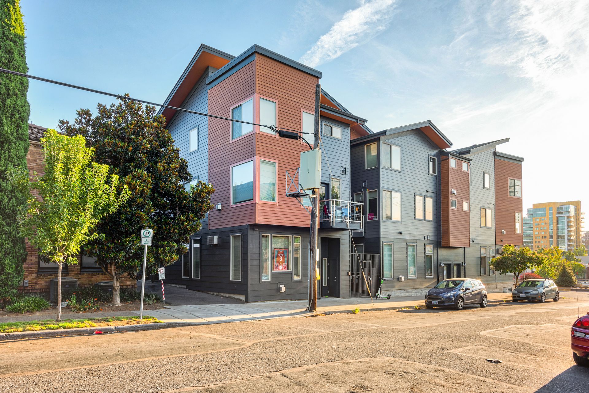 Modern apartment building with red and gray facades on a sunny street corner