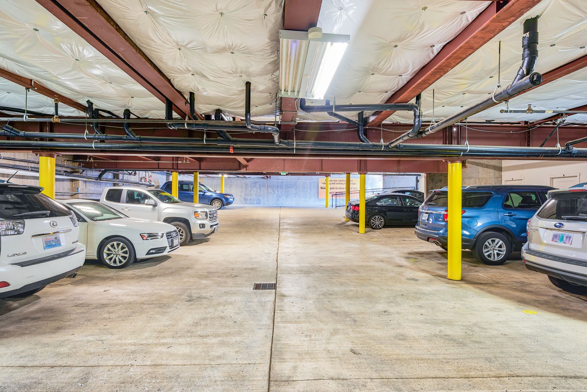 Parking garage with several parked cars and yellow support pillars under a low ceiling