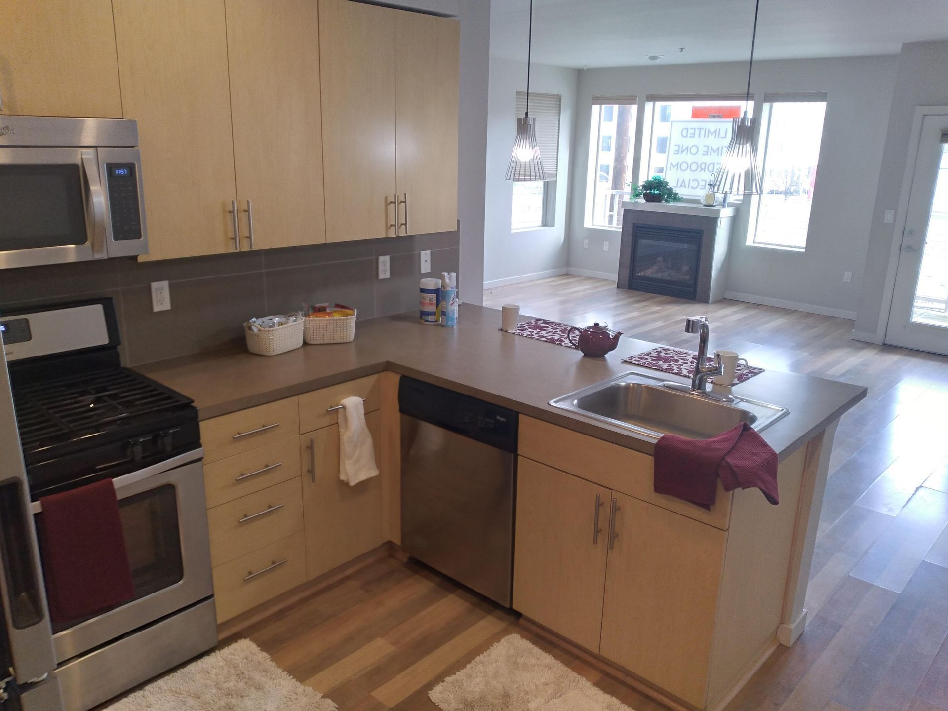 Modern kitchen with wood cabinets, stainless stove, center island sink, and bright windowed dining area