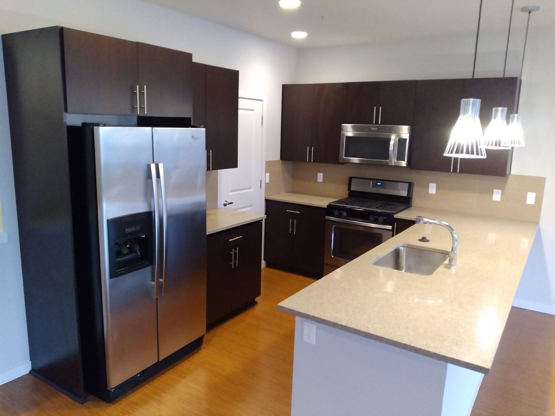 Modern kitchen with dark cabinets, stainless steel appliances, and a light stone island countertop