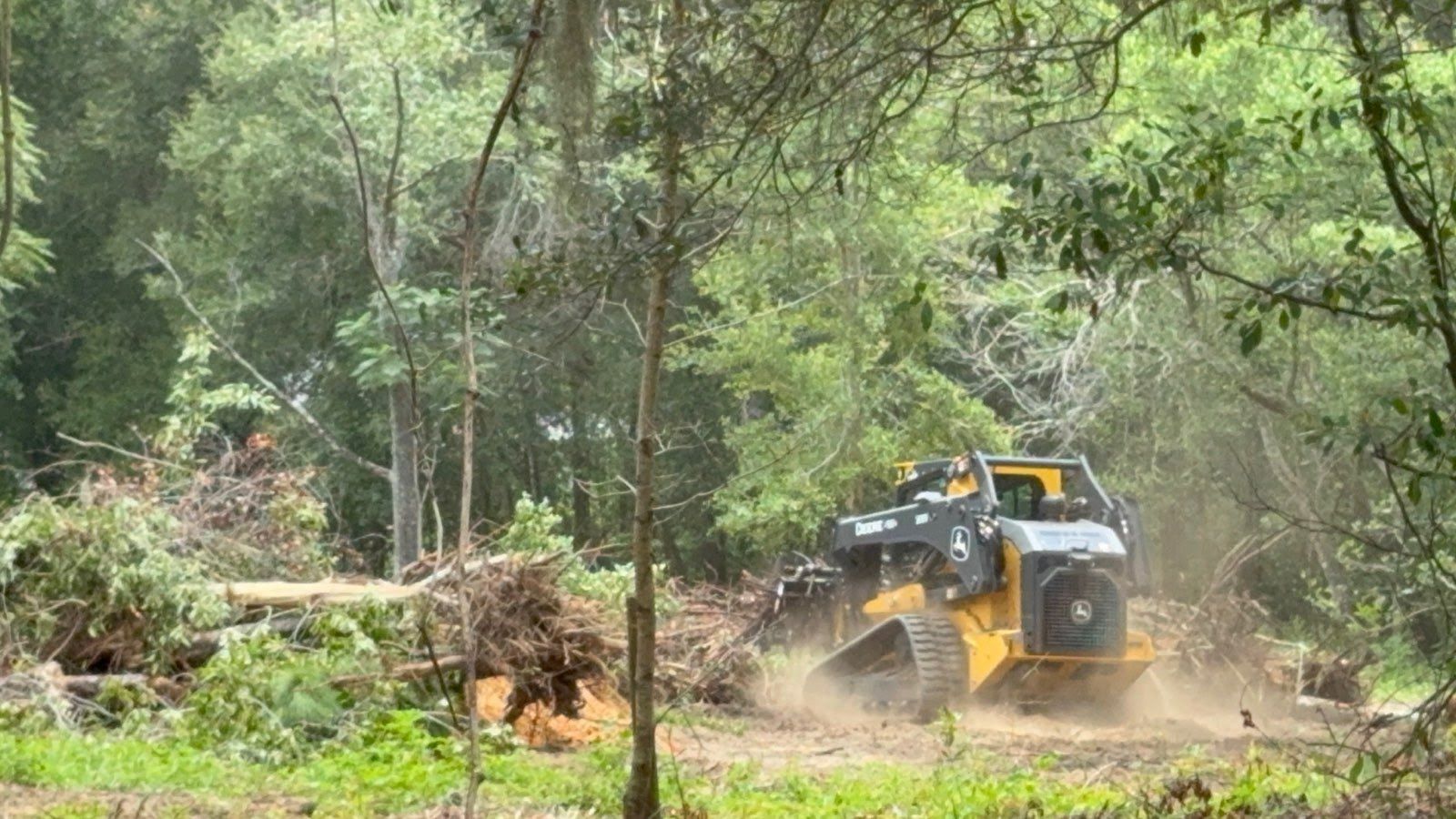 Two yellow excavators working on a construction site, moving sand and soil near trees and heavy equipment. Aerial top-down photo of groundwork, earthmoving and site preparation for development