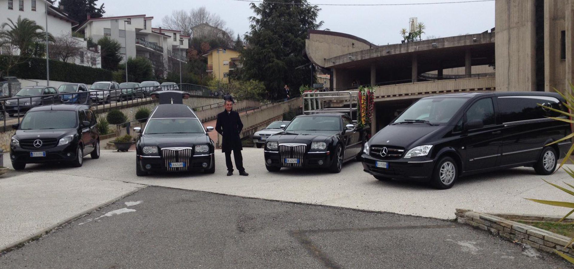 Un uomo è in piedi davanti a una fila di auto nere