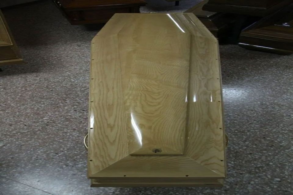 Una bara di legno è appoggiata su un pavimento di marmo.