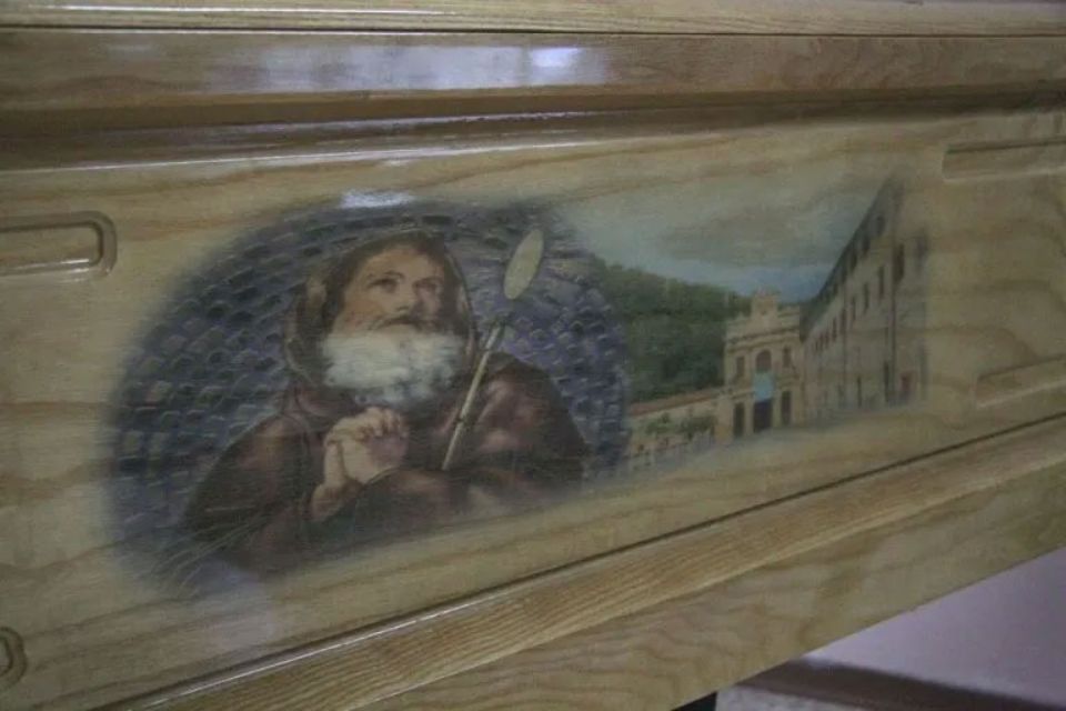 Una scatola di legno con un dipinto raffigurante un uomo con la barba che tiene in mano un bastone.