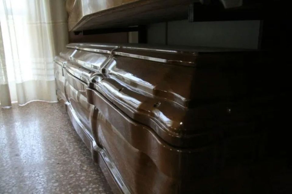 Un baule marrone è appoggiato su un pavimento piastrellato accanto a una finestra.