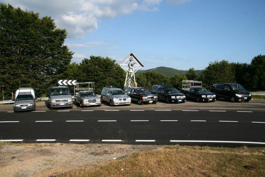 Una fila di auto è parcheggiata sul ciglio di una strada