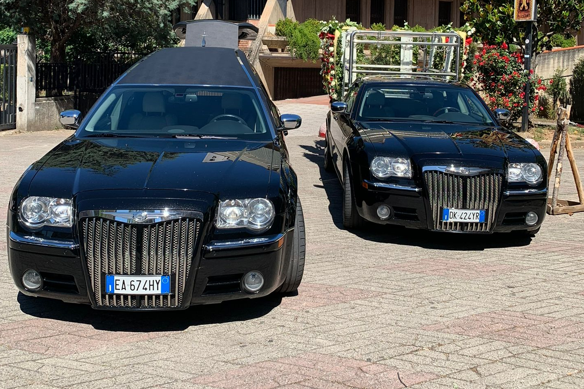 Due auto nere sono parcheggiate una accanto all'altra su una strada lastricata.