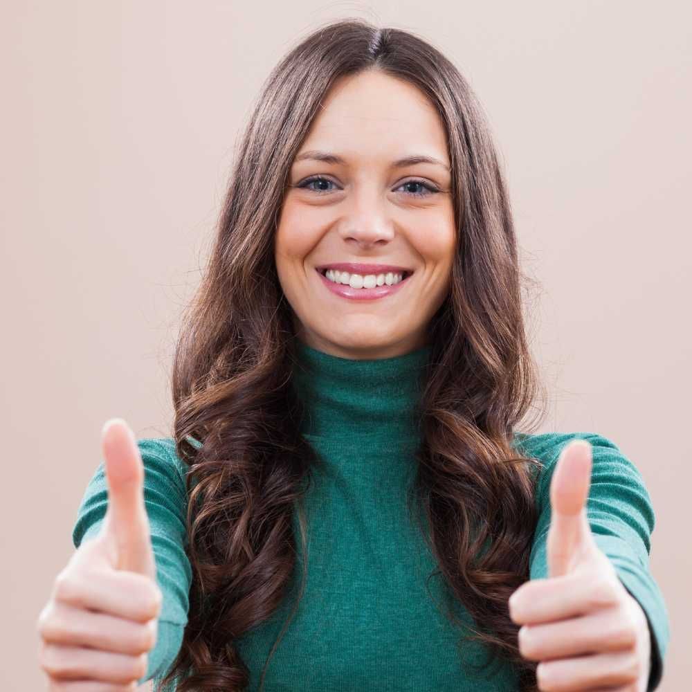A woman in a green sweater is giving two thumbs up.
