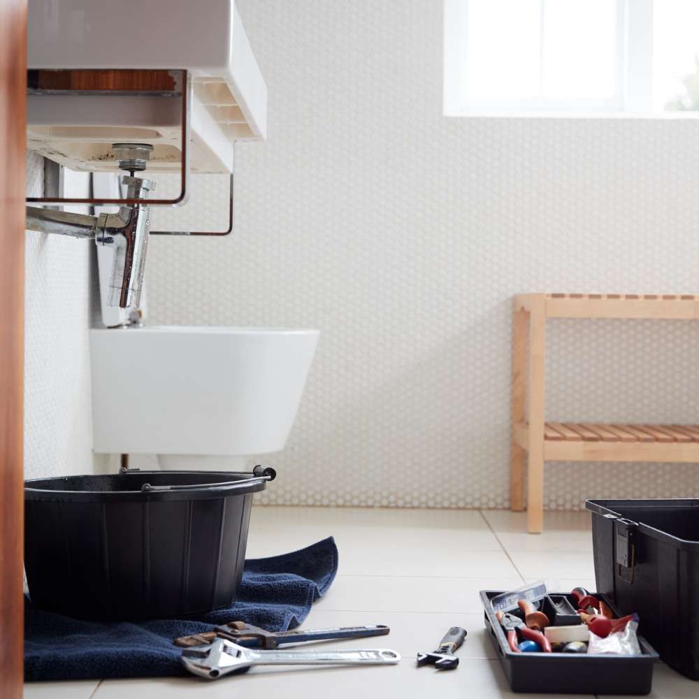 A bathroom with a sink and tools on the floor