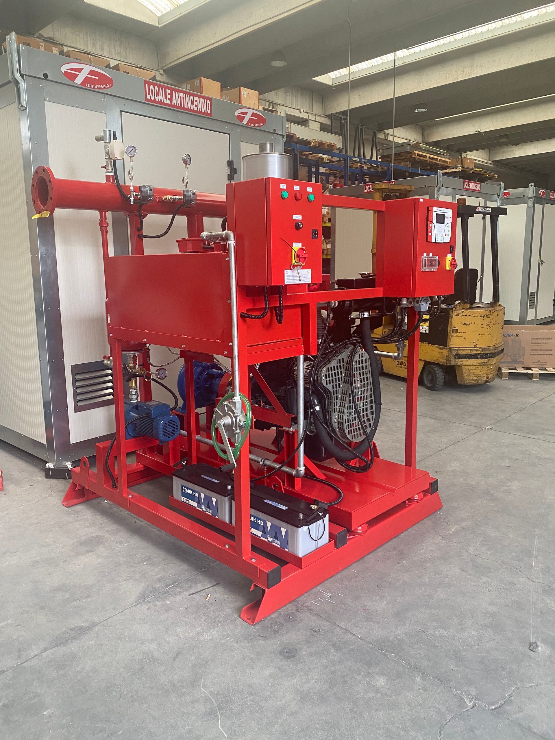 Macchinario industriale rosso su un telaio con ruote in un'officina o in un magazzino.