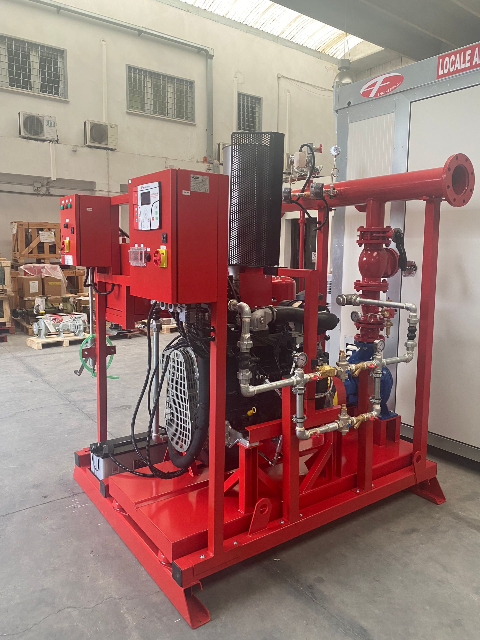 Impianto di pompaggio industriale rosso con tubazioni e scatole di controllo rosse, installato in un'area esterna.