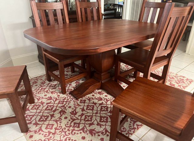 A wooden dining table and chairs are sitting on a rug in a room.