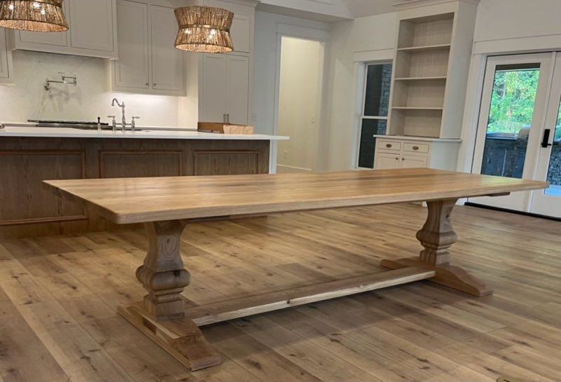 A long wooden table is sitting in a kitchen next to a sink.