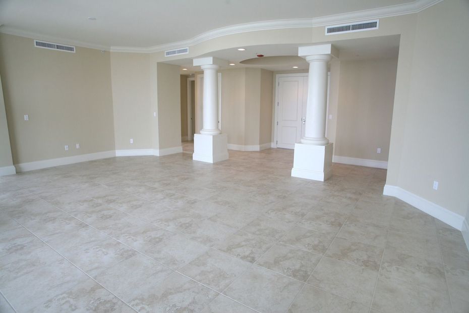 An empty living room with tile floors and white columns