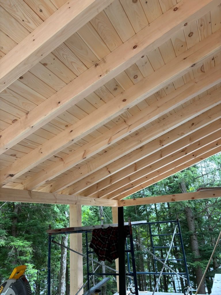 Pavillon au toit en bois avec charpente apparente donnant sur une forêt, avec un fauteuil suspendu en dessous.
