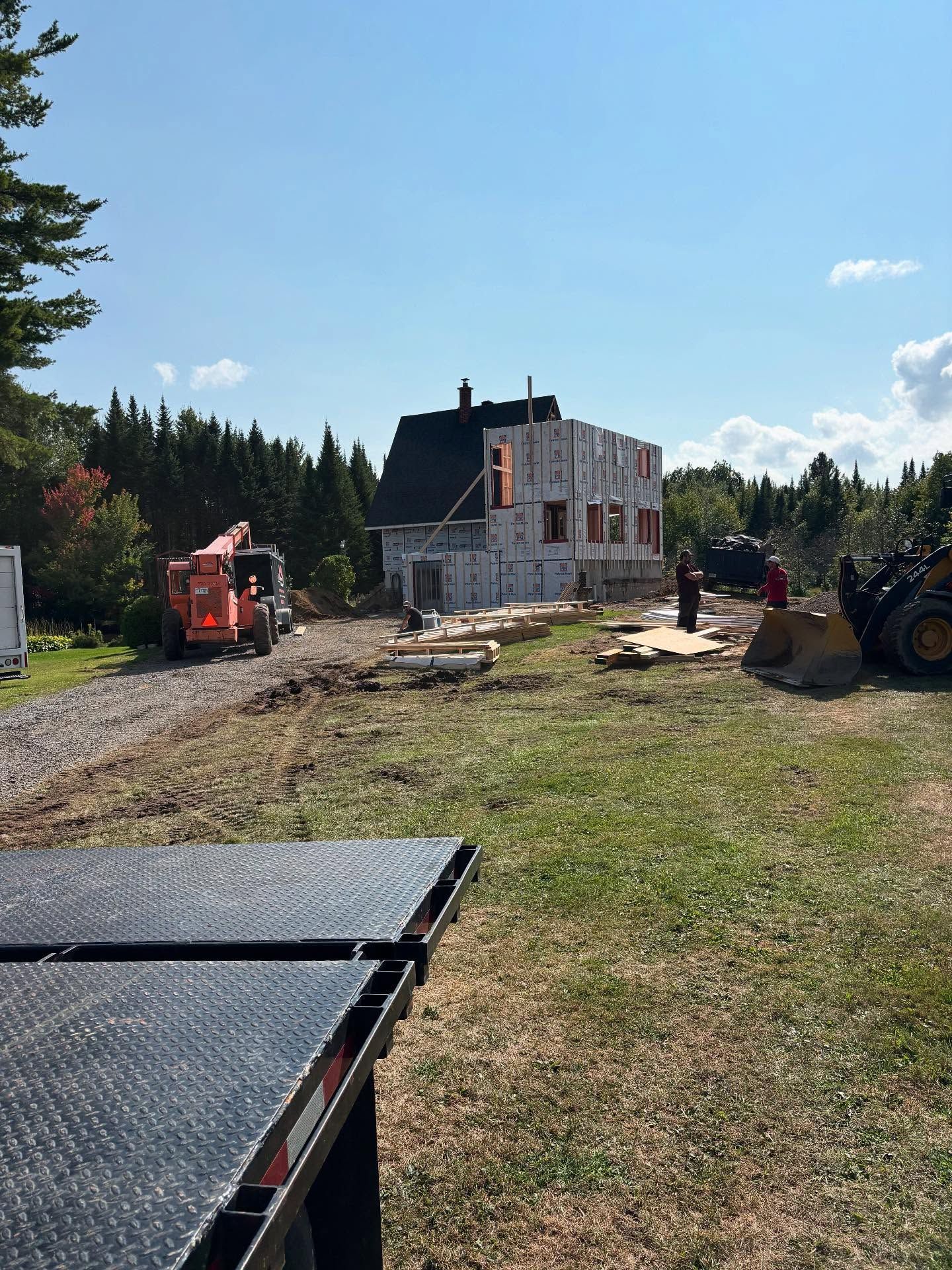 Chantier de construction avec une maison en rénovation, ouvriers et engins de chantier par une journée ensoleillée