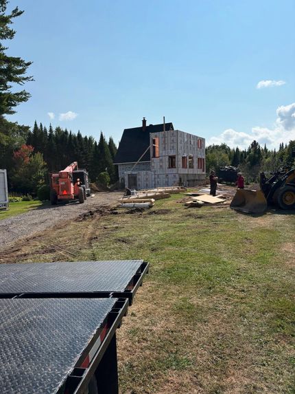Chantier de construction avec une maison en rénovation, ouvriers et engins de chantier par une journée ensoleillée