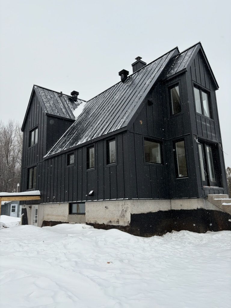 Maison moderne noire aux toits pentus dans un paysage enneigé