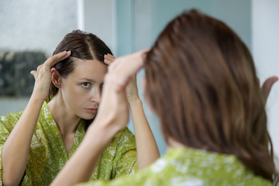 donna mentre applica prodotto per prevenire la caduta dei capelli