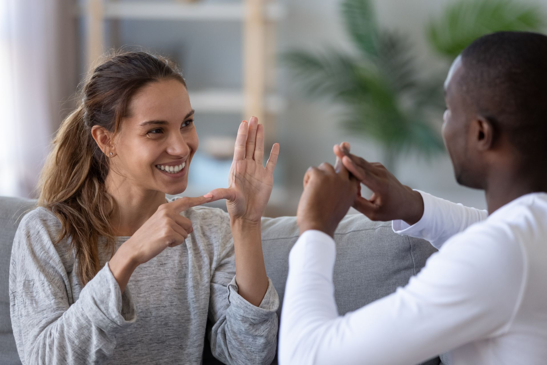 Two people smiling and playing rock-paper-scissors on a couch