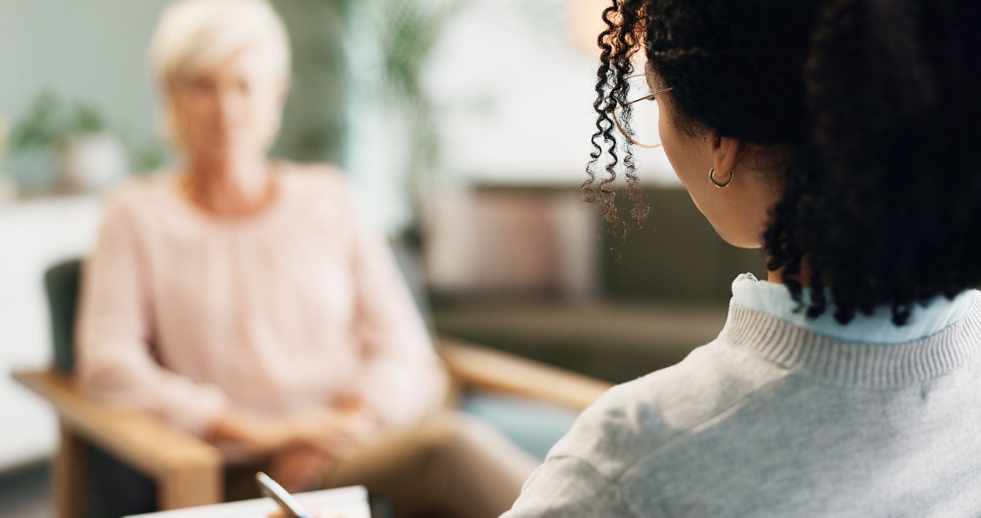 Two people in a counseling session, seated across from each other in a softly lit room.