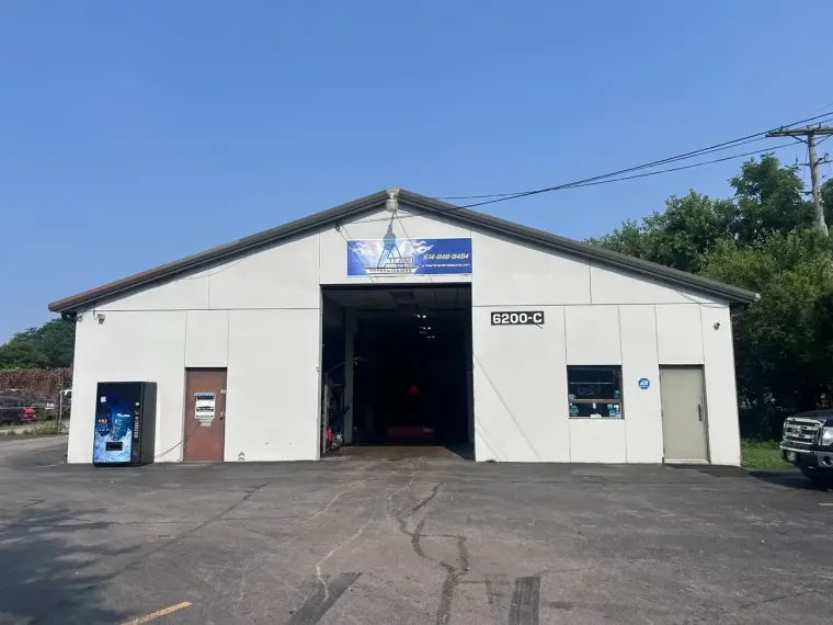 Auto repair shop exterior with parked Jeep and motorcycles on a snowy street