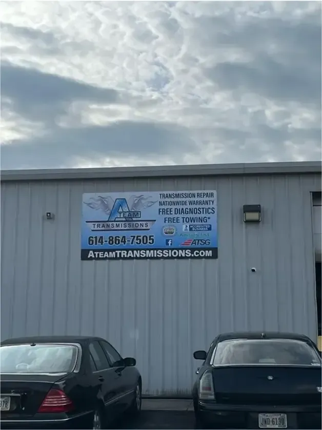 Lifted purple Jeep parked outside an auto repair shop under a billboard.