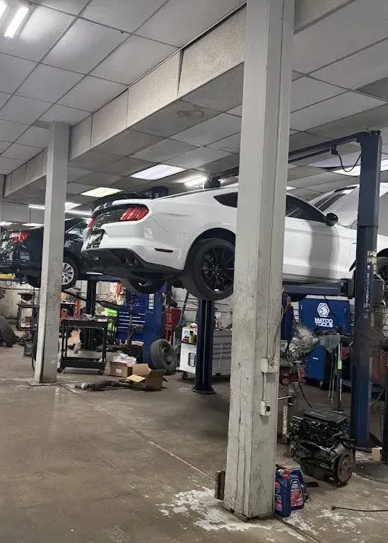 White SUV lifted on a garage hoist inside an auto repair shop