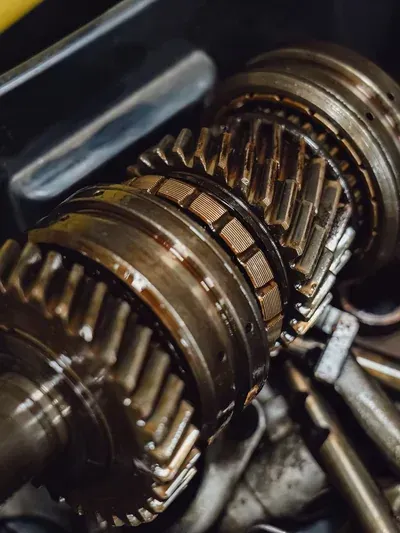 Close-up of a metal gearbox with interlocking gears and shafts inside a machine.